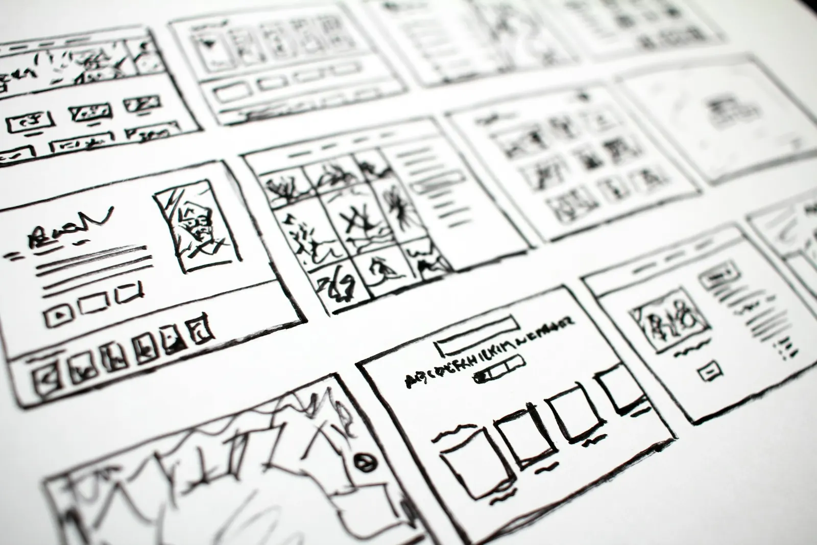Bocetos de wireframe desenfocados sobre una mesa, representando el prototipo de validación